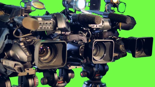 Row professional video cameras on tripods.