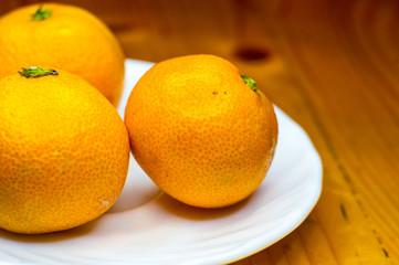 tangerines in white saucer on wooden table