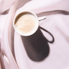 top view of cup of coffee on pink tablecloth with shadow
