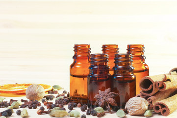 Essential oils in glass bottles and spices on wooden background with copyspace