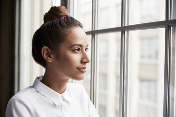 Young businesswoman with hair bun looking out of window