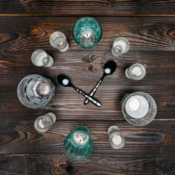 Top View Of Circle With Different Sized Glasses With Water And Spoons On Wooden Table