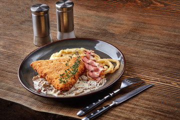 Chicken schnitzel with herb, mashed potatoes and mushrooms sauce on plate on wooden table background. Healthy food.
