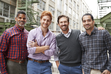 Four male coworkers smiling to camera outside