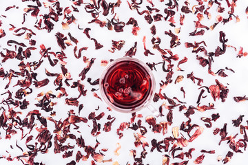 top view of cup with hibiscus tea between scattered tea isolated on white