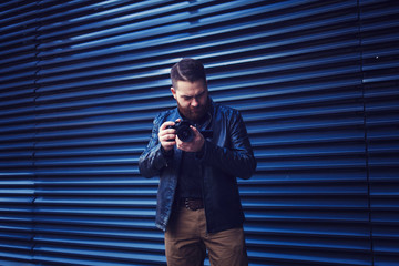 Fototapeta na wymiar stylish man photographer in a leather jacket on a blue background