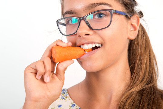 beautiful girl with  carrot. Vitamins for teenagers. Vegetabl for healthy eating of children. Positive weight loss. Portrait of  girl with carrot. girl with glasses. girl bites a carrot