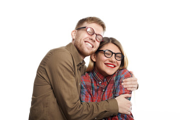 Portrait of joyful cute young European girlfriend and boyfriend wearing similar stylish oval shaped glasses cuddling, their broad smiles expressing happiness and joy. So happy to be together