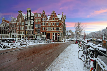 Fototapeta premium Snowy Amsterdam in the Netherlands in winter at sunset