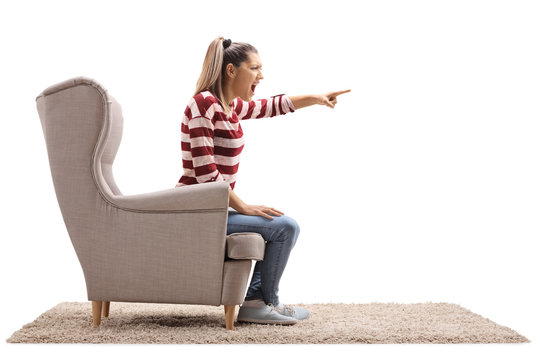Angry young woman sitting in an armchair and arguing