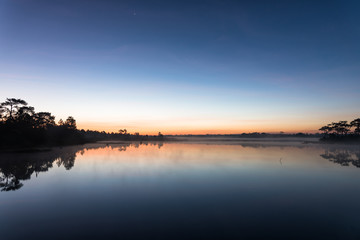 Morning sunrise over the lake with silhouette tree reflect on water surface at Phu Kradaung, national park in Thailand.