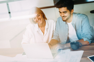 Fototapeta premium Handsome young man and attractive woman working on laptop