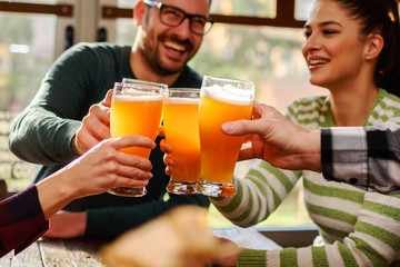 Smiling young people drinking craft beer in pub
