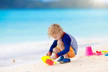 Kids play on tropical beach. Sand and water toy.