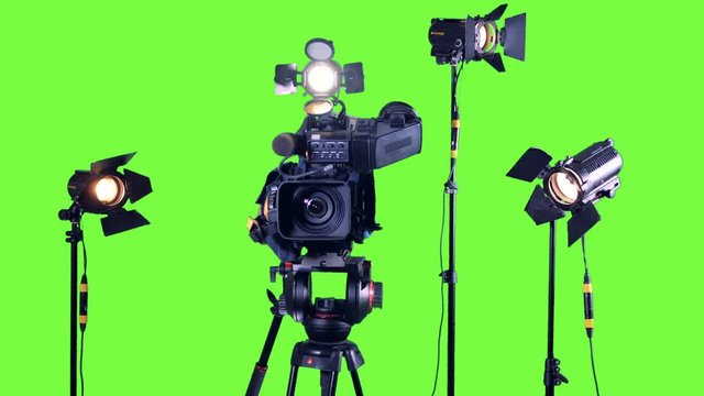 Professional studio spotlights and a professional video camera on a green screen.
