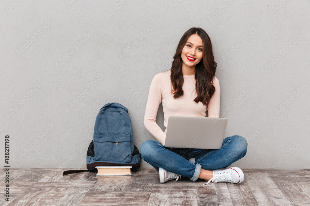 Wall mural attractive female with beautiful smile studying using silver notebook while sitting in lotus pose on