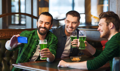 friends taking selfie with green beer at pub