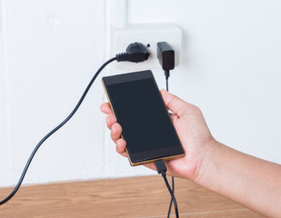 Hand holding a Mobile phone in charging plugged