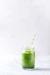 Green spinach kale apple yogurt smoothie in mason jar with retro cocktail tubes over white background. Healthy vegan detox eating.