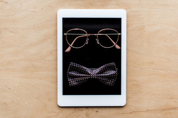 top view of glasses and tie bow on tablet