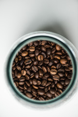 top view of glass bottle with coffee beans on white