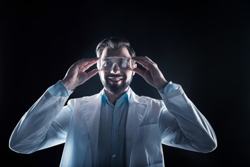 Professional science. Joyful nice happy man smiling and wearing safety glasses while working as a scientist