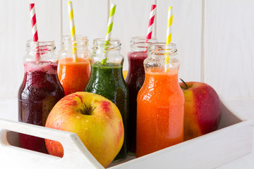 Detox drinks in bottles: fresh smoothies from vegetables: beet, carrot, spinach, cucumber and apple on white background