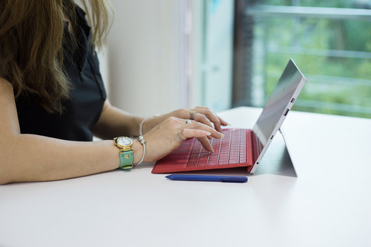 Business woman hand typing on surface pro in office in front of green background