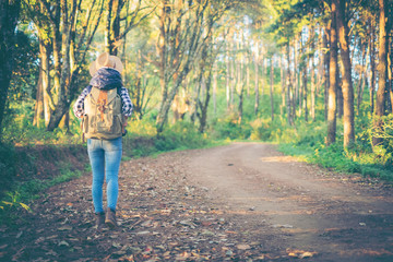 Young hiker woman with backpack on a forest trail in the mountains. Young woman traveller with backpack in a woods. Hiking at summertime.