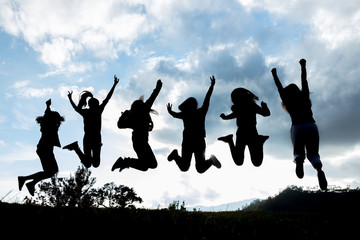 silhouette group of young people is jumping on top of the mountain