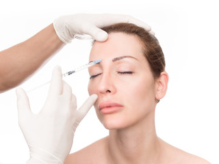 Close up of hands of cosmetologist injecting botox in female face. The woman is closed her eyes with relaxation.