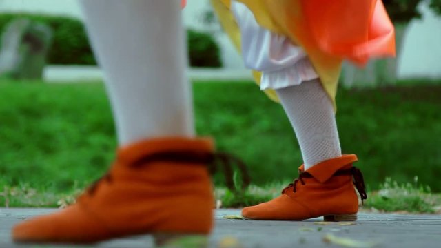 People dancing foots in orange Irish national clothing. Closeup of feets dancing Irish national dance. Folklore dancers background. National entertainment