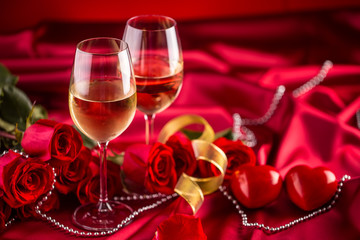 Valentines or wedding concept. Wine cups red roses and romantic setting for two in red. Greeting card for jubilee or aniversary