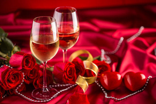 Valentines or wedding concept. Wine cups red roses and romantic setting for two in red. Greeting card for jubilee or aniversary