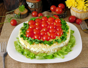 Layered salad decorated with cherry tomatoes and lettuce leaves on a white plate