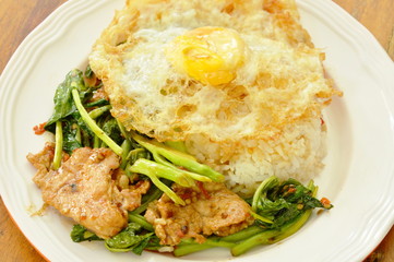 spicy stir fried Chinese kale with pork topping egg on rice