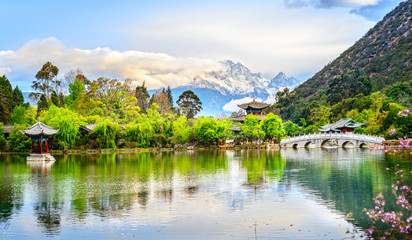 Fototapeta na wymiar Black Dragon Pool and Jade Dragon Snow Mountain. It's a famous pond in the scenic Jade Spring Park (Yu Quan Park) located at the foot of Elephant Hill, old Town of Lijiang in Yunnan, China.