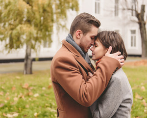Fototapeta premium Young couple in love holding hands and walking through a park on a sunny autumn day