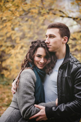 Fototapeta premium Young couple in love holding hands and walking through a park on a sunny autumn day