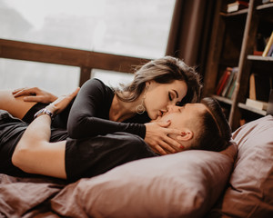 Obraz na płótnie Canvas Loving couple. Handsome young hipster and attractive woman resting at home while sitting on bed at home