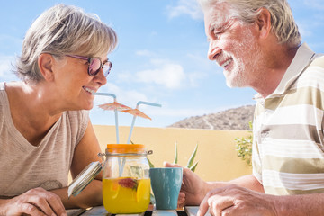 Elderly couple drink together forever a fruit juice on the terrace