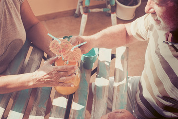 Obraz premium Senior couple drink a fruit juice together under the sun
