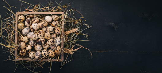 Quail eggs in a wooden basket. On a wooden background. Top view. Copy space.
