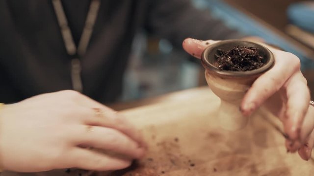 man fills hookah cap by tobacco