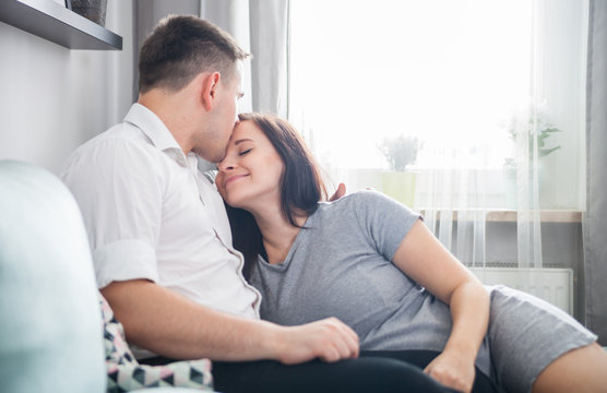 Cheerful pregnant couple relaxing at home and enjoying pregnancy time