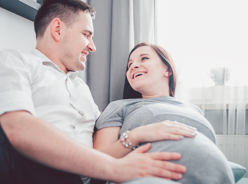 Cheerful pregnant couple relaxing at home and enjoying pregnancy time