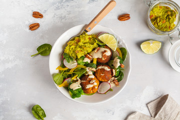 Vegan baked sweet potato meatballs, guacamole and vegetables salad. Light background, healthy vegetarian food concept, copy space, top view.