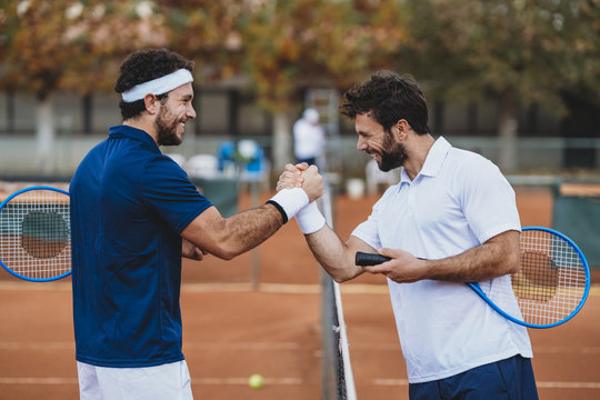 Two young men handshake after a tennis match on a clay court