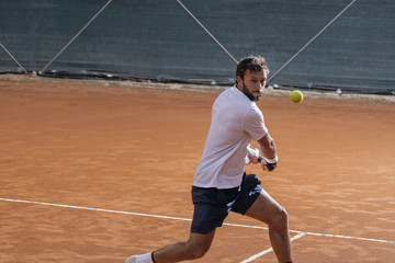 Young man playing tennis on a clay court
