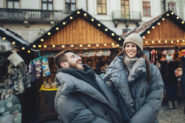 Happy couples on the city square decorated for a Christmas marke 